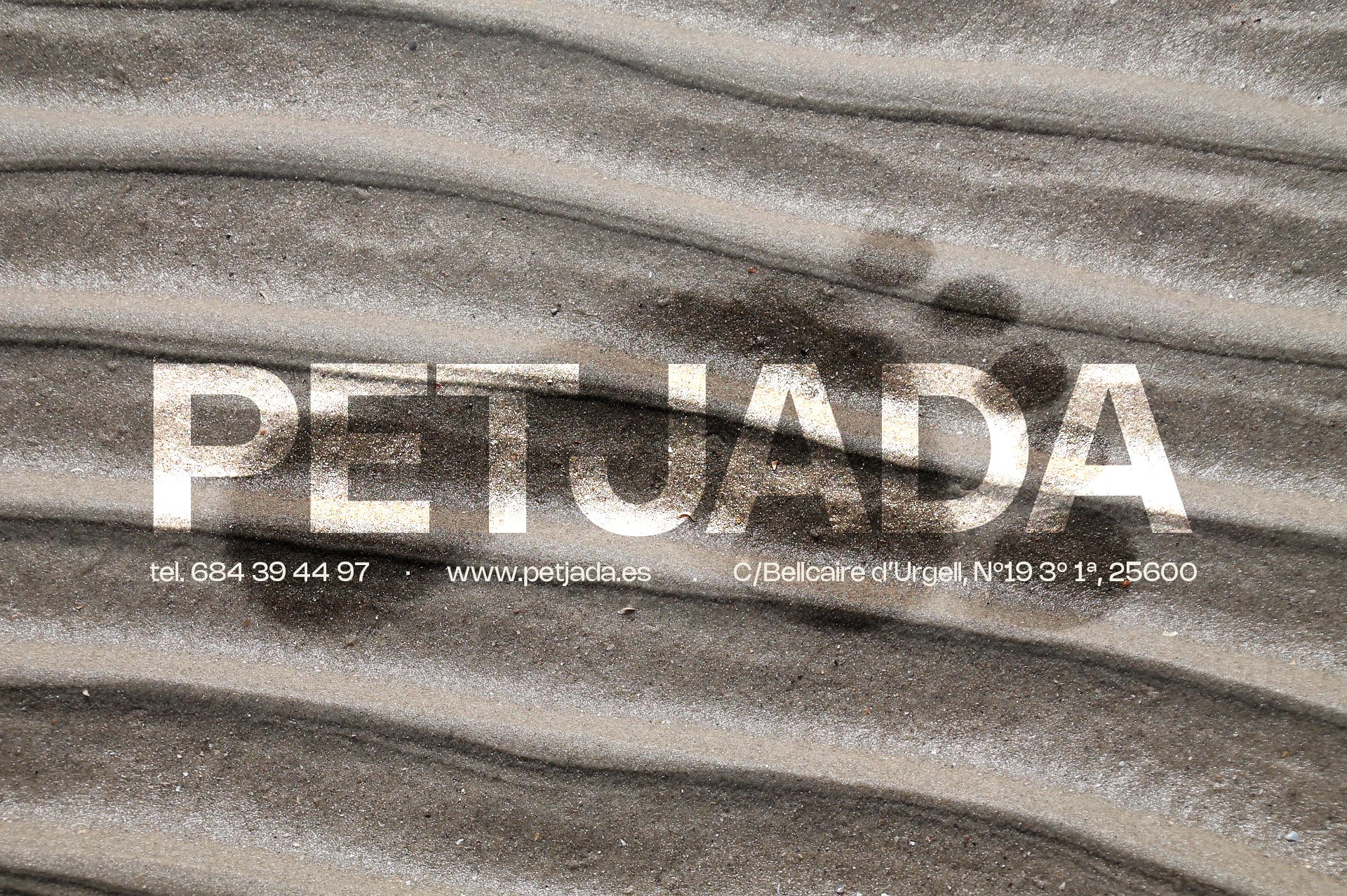 petjada-background-arena Arena mojada con una huella y el logo de PETJADA en el centro.